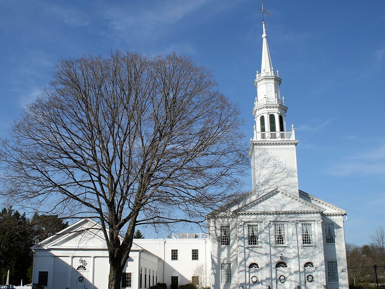 Avon CT church steeple and leafless tree under blue sky
